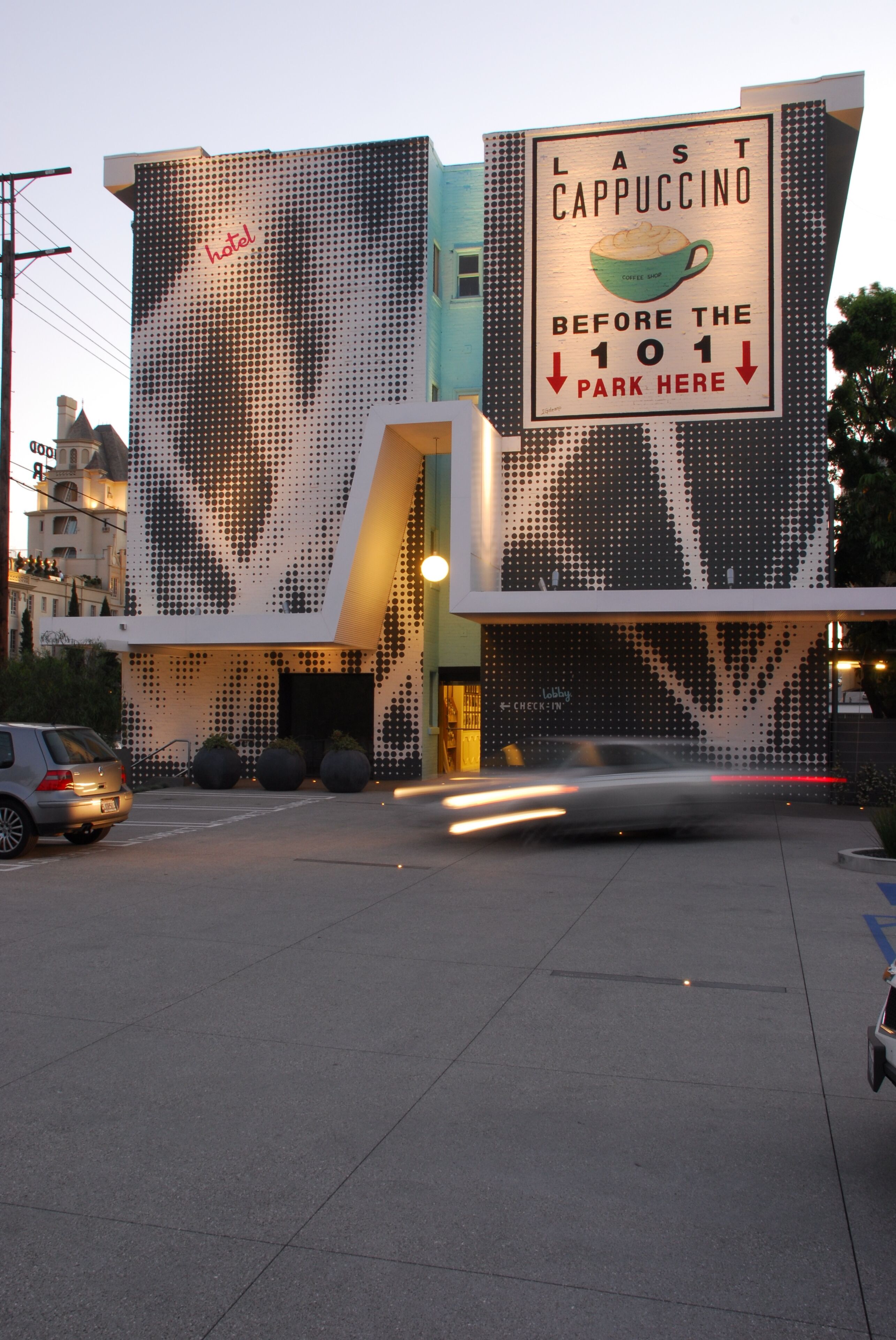 Un bâtiment moderne doté d’une façade originale ornée d’un motif à pois et d’une enseigne bien visible qui fait la publicité du dernier cappuccino servi avant le parking 101.