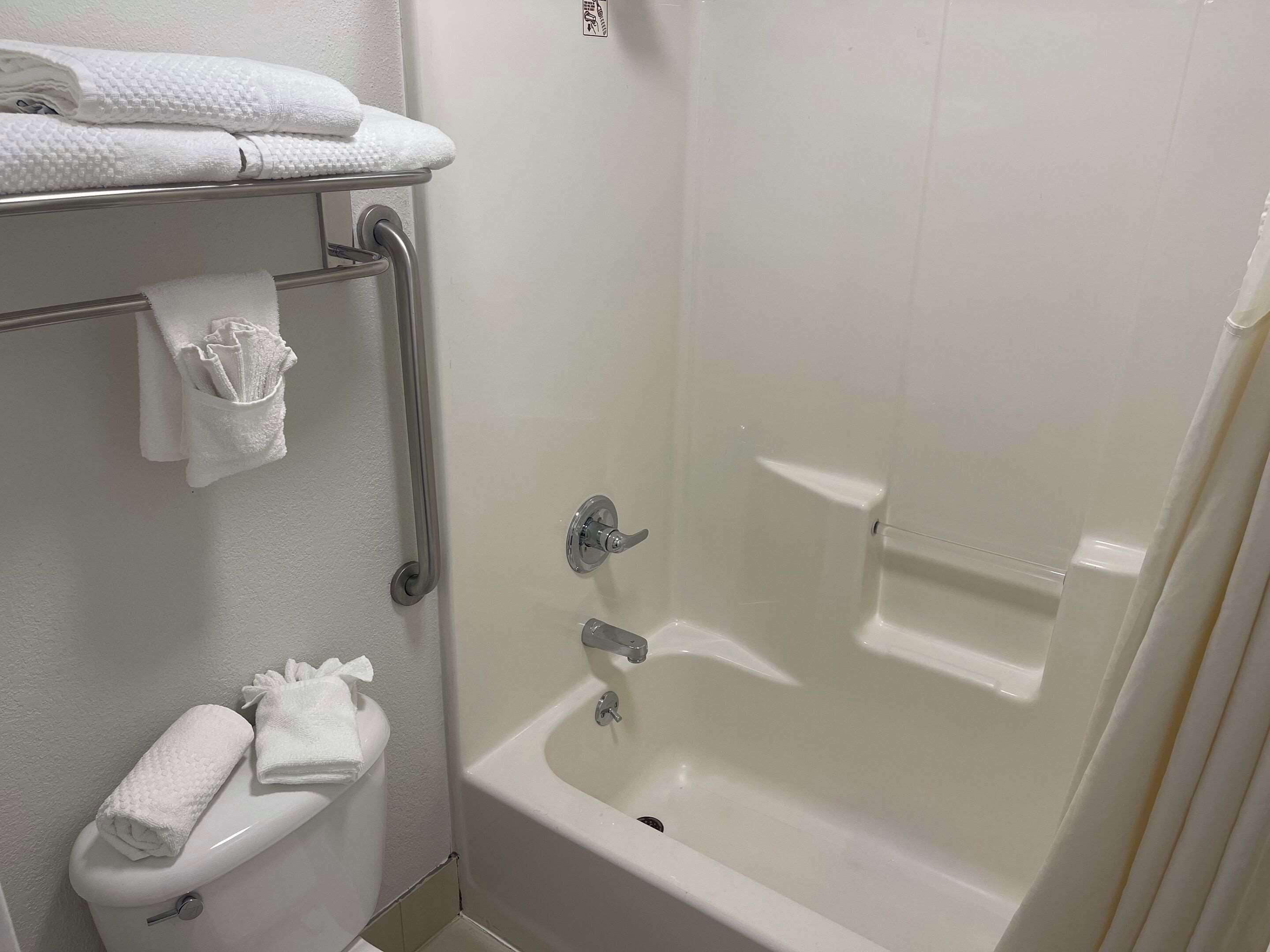 A bathroom with a toilet, a towel rack, and a bathtub.