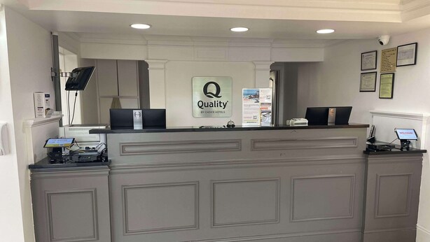A reception desk with a sign reading "Quality by Choice Hotels," a computer, and a "WELCOME" sign. - Quality Inn Dalton Central (Dalton)