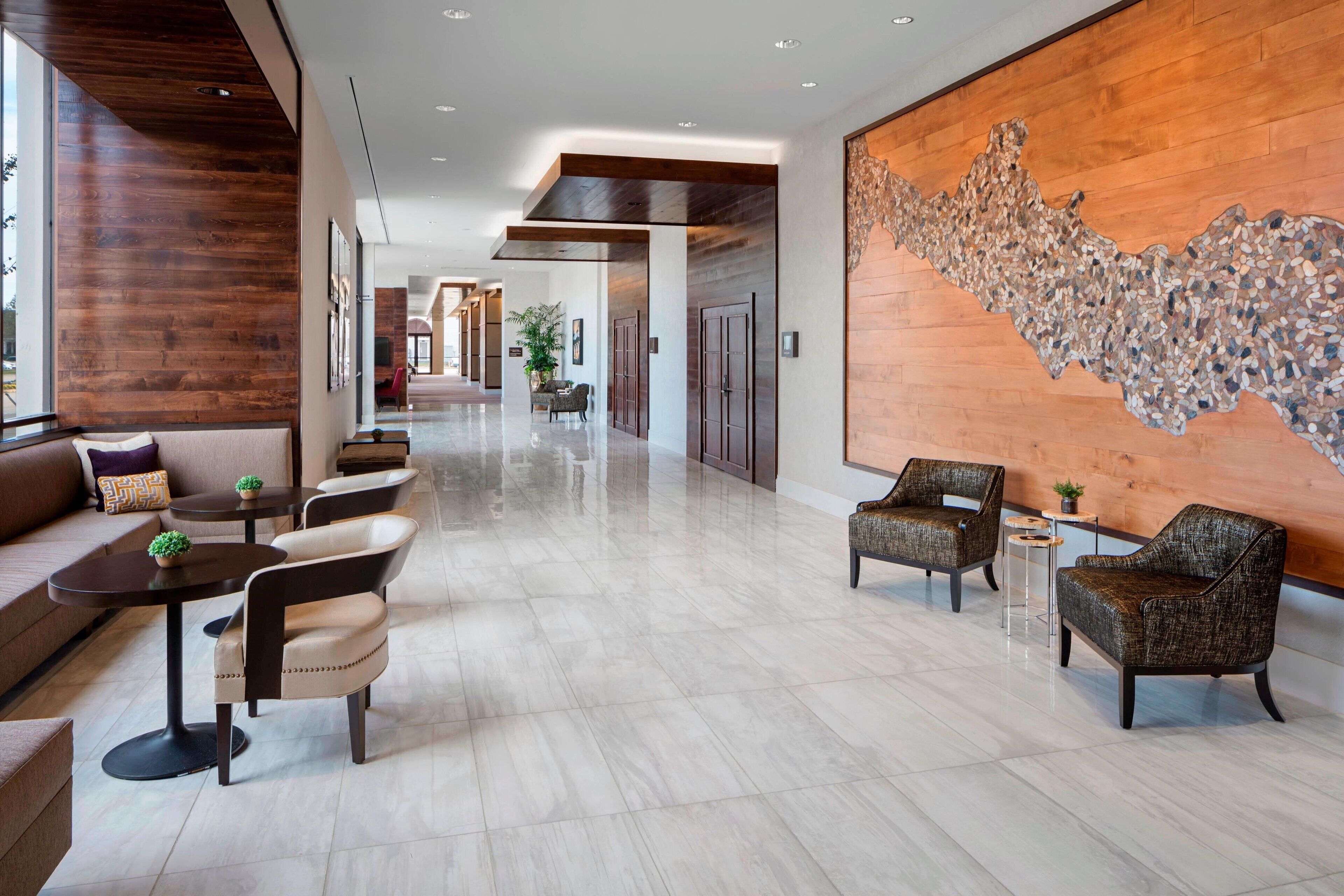 Eine geräumige Lobby mit einer langen Korridor, Sitzbereiche mit Sofas und Sesseln sowie einer großen Dekowand.