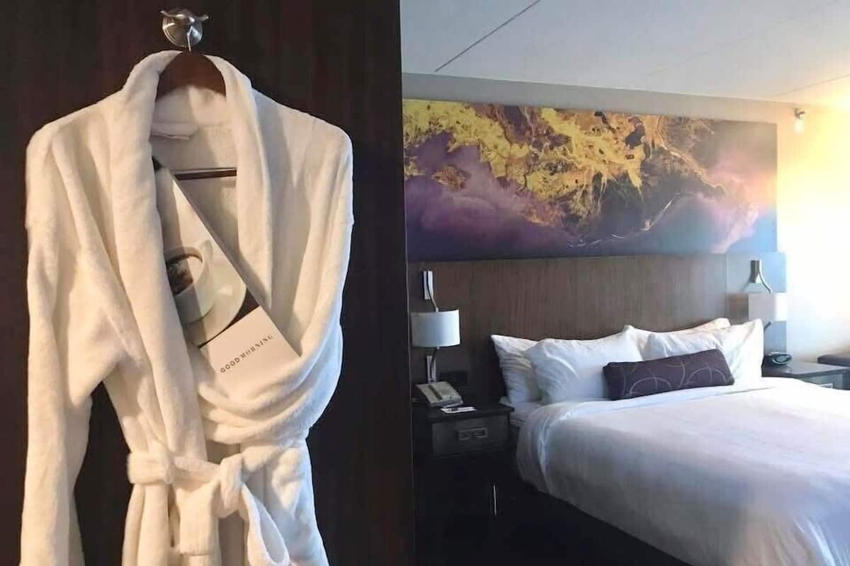 A hotel room with a bed, nightstands, and a robe on a rack.