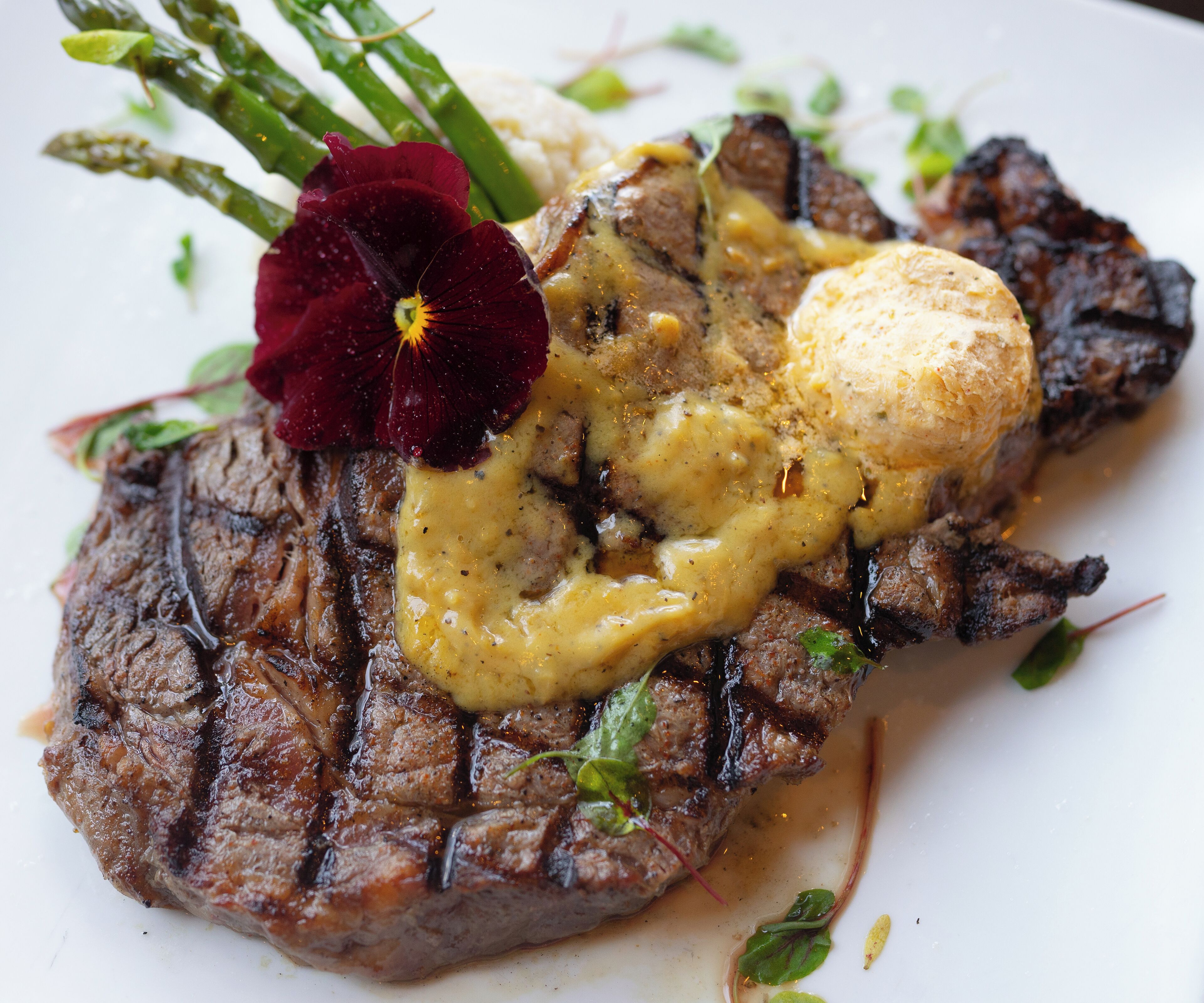 Bife com molho cremoso e um pedaço de manteiga no prato.