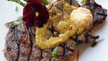 Bife com molho cremoso e um pedaço de manteiga no prato.