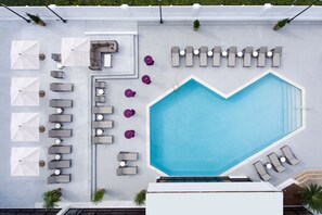 An aerial view of a rooftop pool area with a heart-shaped pool, sun loungers, and umbrellas. - Marriott Baton Rouge (Baton Rouge)