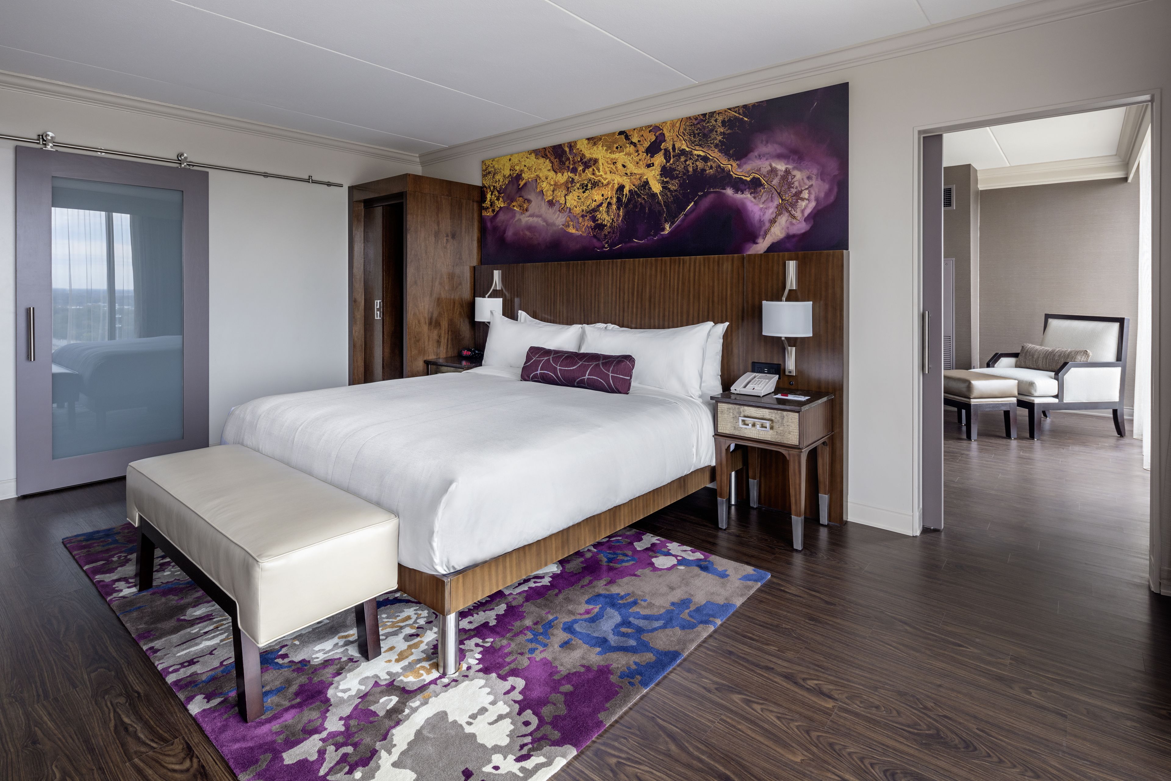 Ein modernes Hotelzimmer mit einem großen Bett, einem Nachttisch mit Lampe, einem Beistelltisch und einem Sessel.