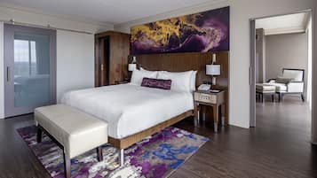 Ein modernes Hotelzimmer mit einem großen Bett, einem Nachttisch mit Lampe, einem Beistelltisch und einem Sessel.