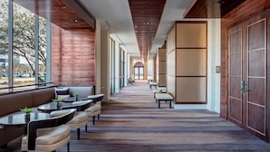 A modern hotel lobby with a long corridor, seating areas, and large windows.