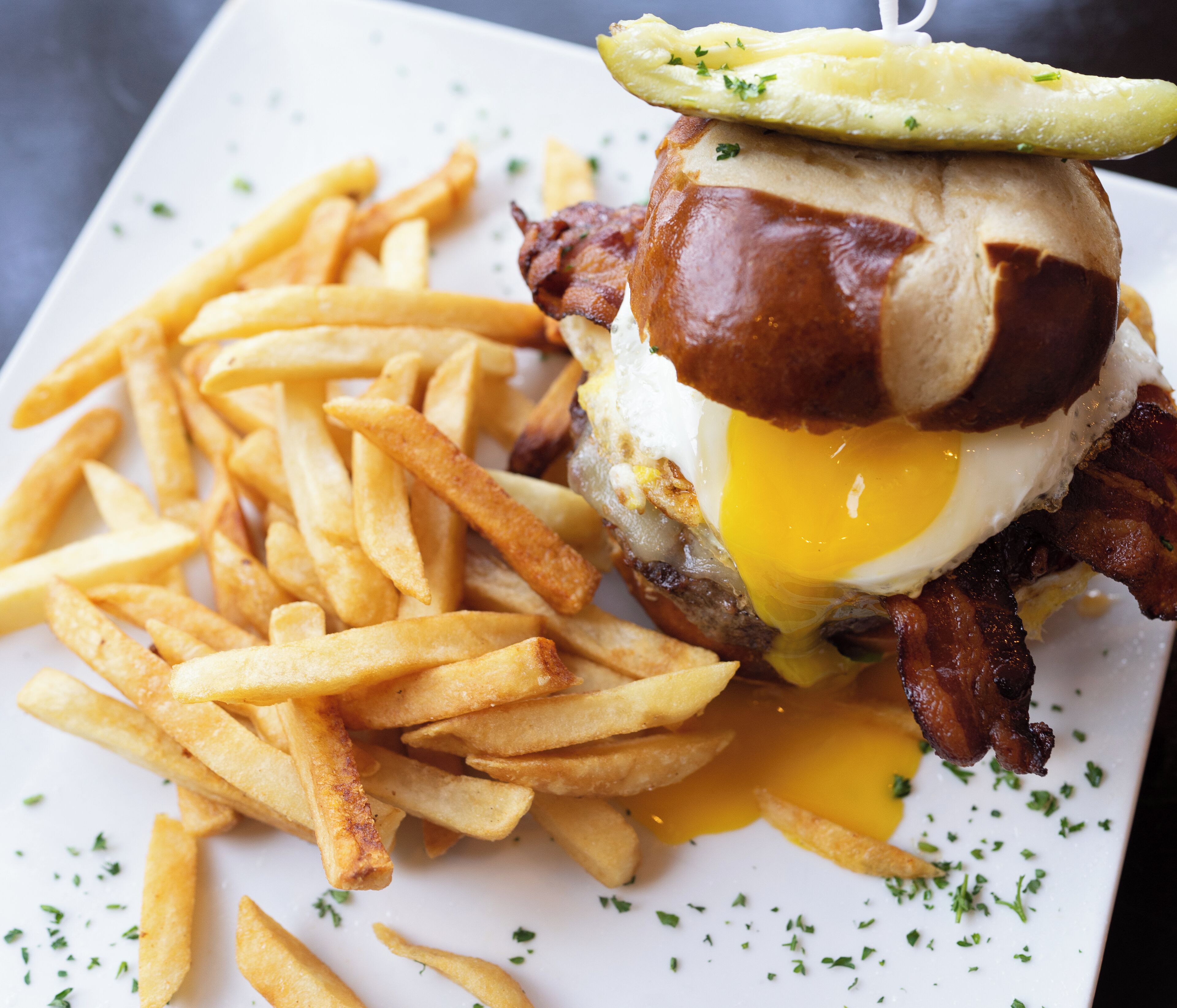 Un sándwich con tocino, huevo y queso, acompañado de papas fritas.