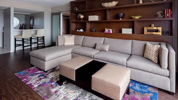 A modern living room with a sectional sofa, ottomans, a coffee table, and a bookshelf.