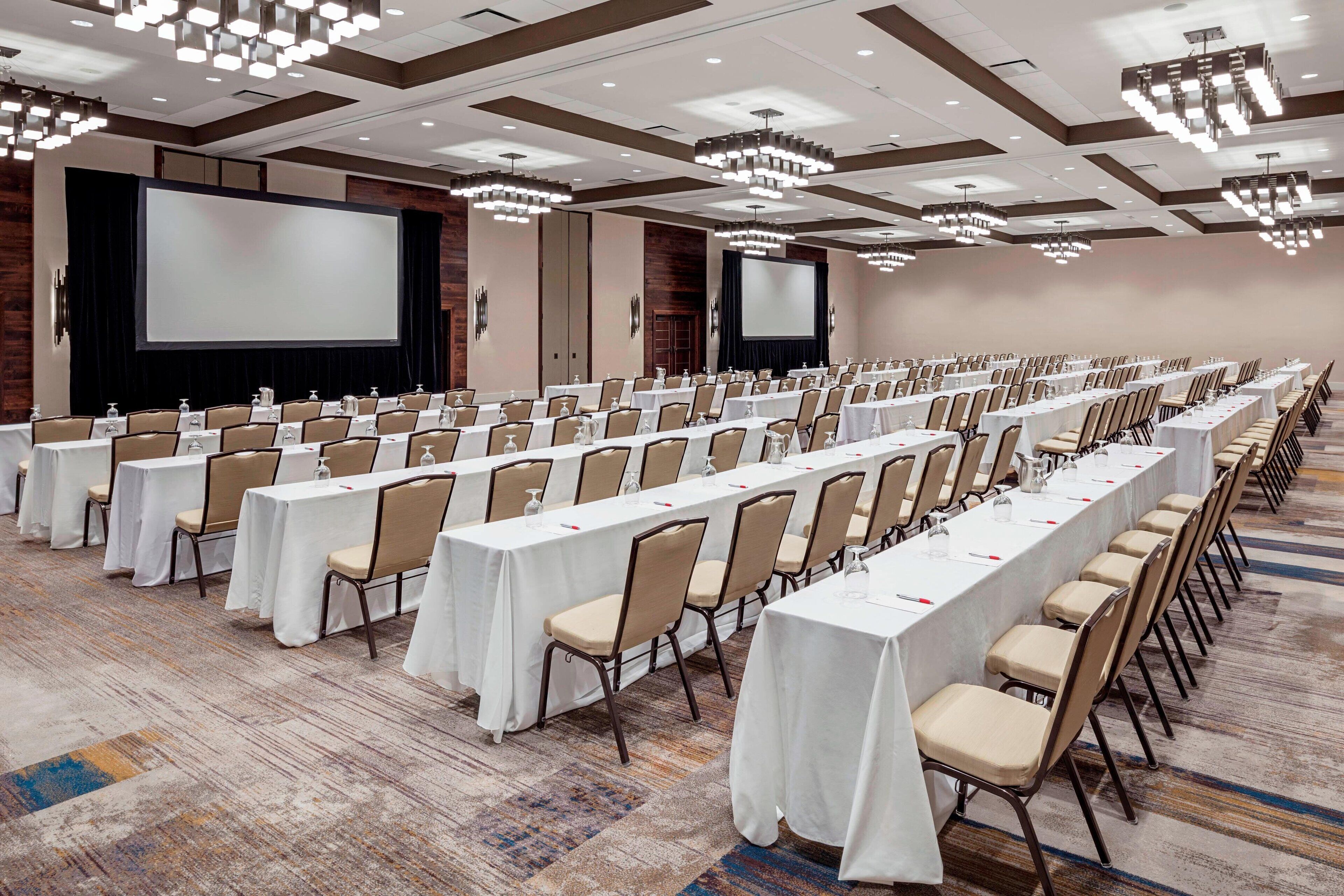 Une salle de conférence équipée de longues tables, de chaises et d’un grand écran.