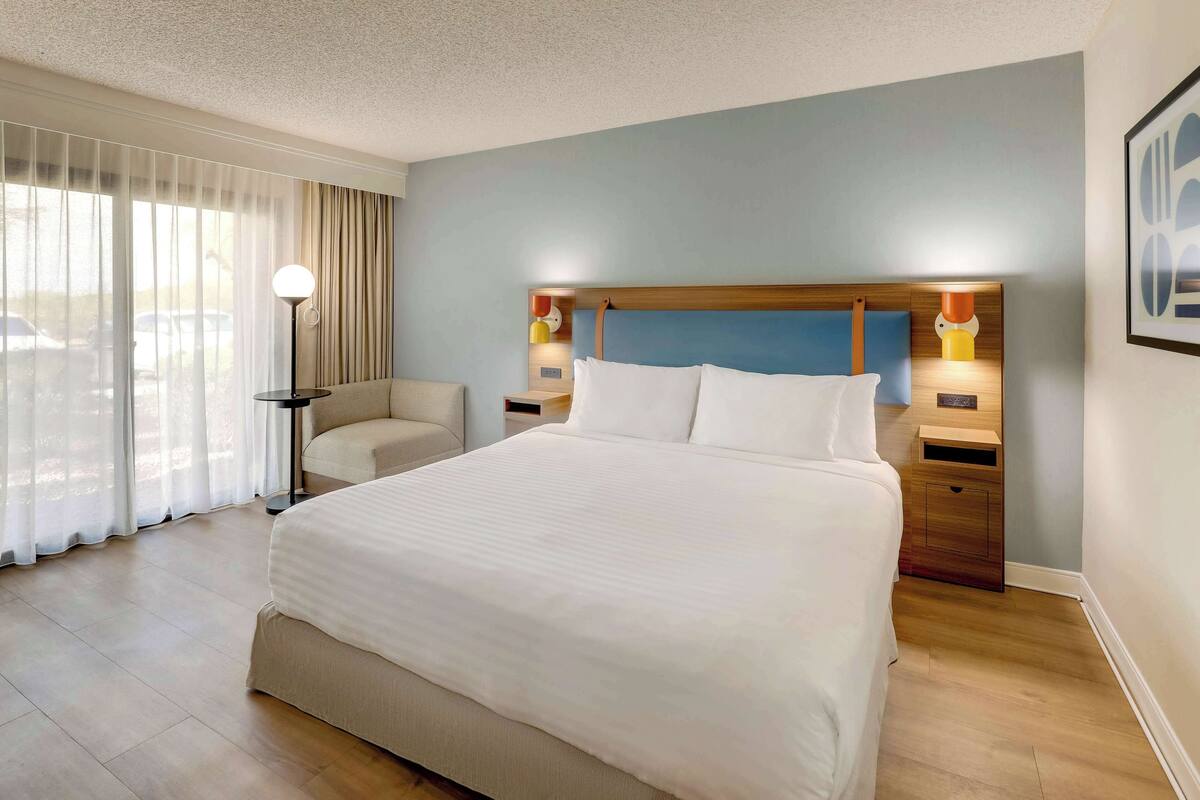 Een hotelkamer met een groot bed, een stoel, een bureau en een lamp.