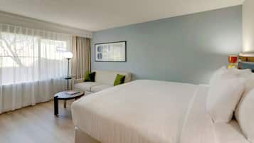 A hotel room with a large bed, a sofa, a small table, and a lamp.