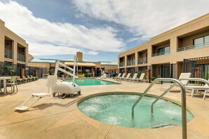 Ein Poolbereich mit zwei Pools, Liegestühlen und einer Wasserrutsche.