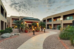 A hotel courtyard with a central pathway, potted plants, and a building with multiple balconies and windows. - Sonesta Select Scottsdale at Mayo Clinic Campus (Scottsdale)