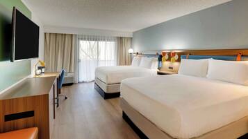 Een hotelkamer met twee bedden, een bureau met stoel, een flatscreen televisie en een raam met gordijnen.