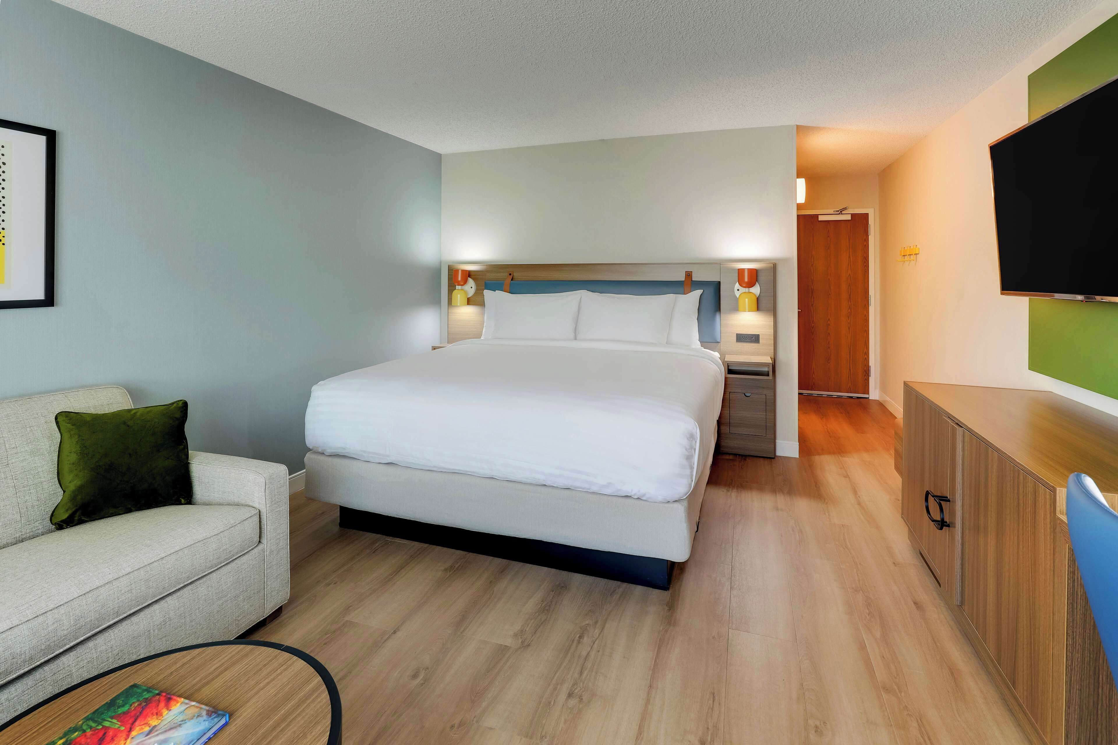 Une chambre d’hôtel moderne équipée d’un lit, d’un canapé, d’un bureau et d’une télévision.