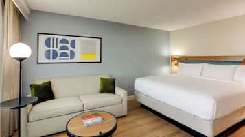 Una habitación de hotel con una cama, un sofá, una mesa de centro y una lámpara de pie.