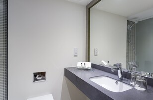 Un baño moderno con un espejo grande, lavabo doble y zona de ducha.