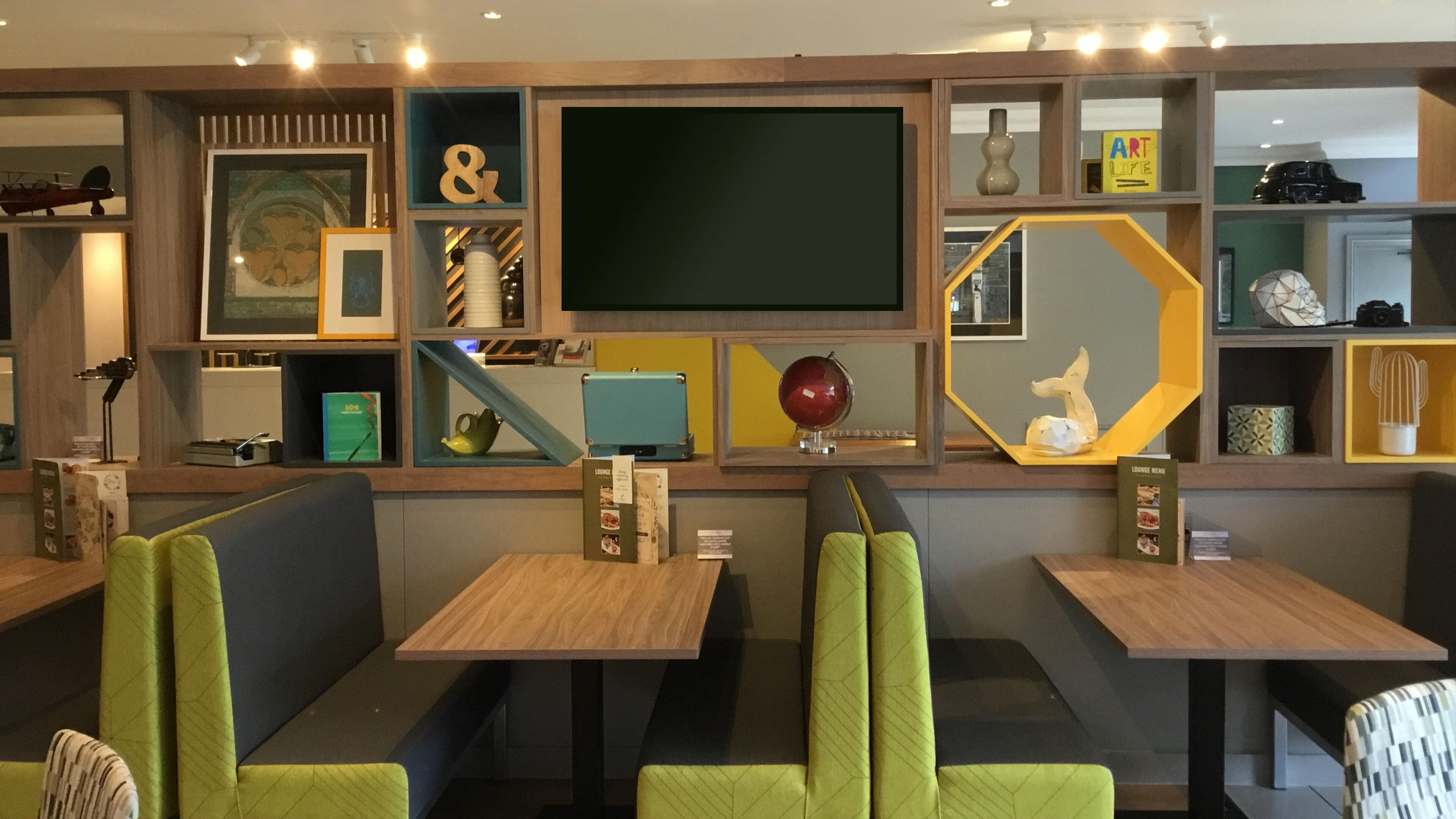 A modern lounge area with seating, a large flat-screen TV, and various decorative items.
