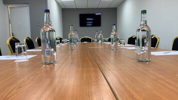 A conference room with a long wooden table, clear glass bottles, and chairs.