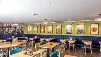 A restaurant interior with booths and tables, green walls, and travel-themed posters.