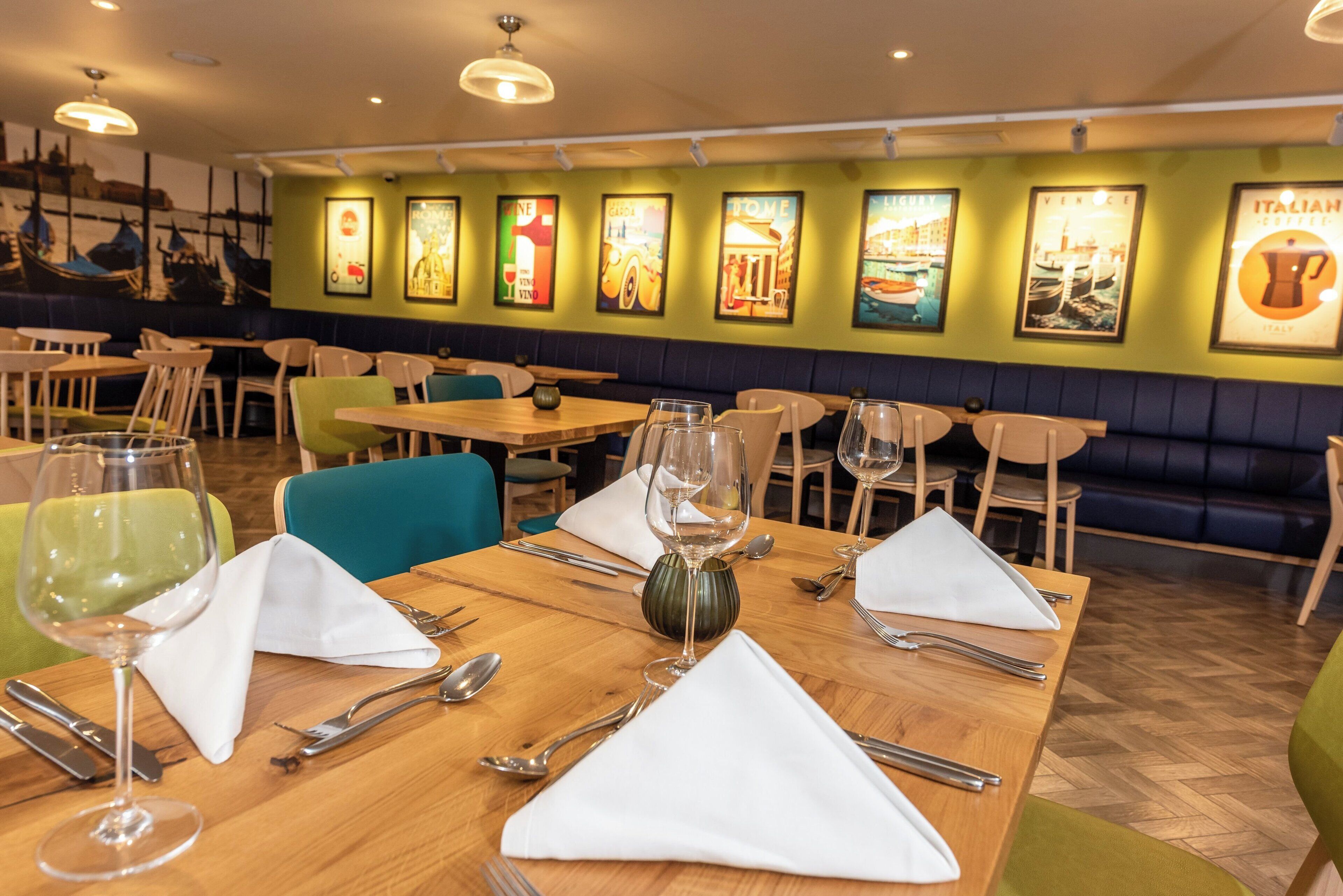 A restaurant interior with wooden tables, chairs, and a wall adorned with framed pictures.