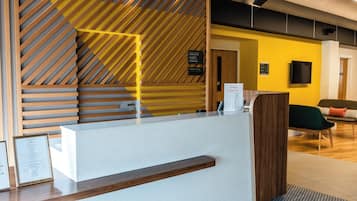 Ein Hotelrezeptionstresen mit modernem Design, inklusive einer Wand aus Holzlamellen und einer weißen Theke.