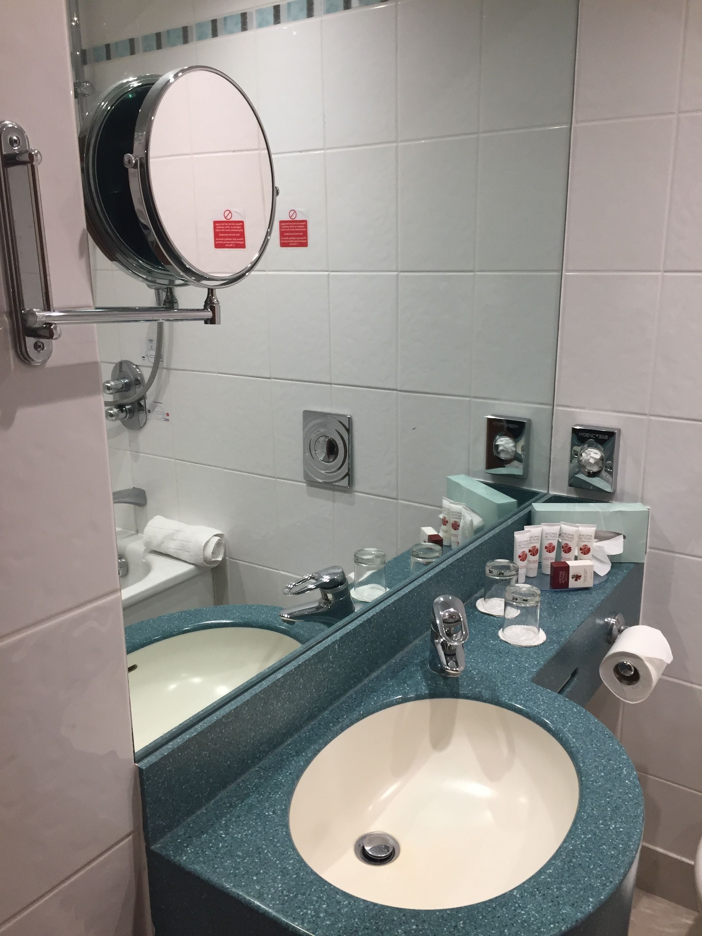 Un baño con dos lavamanos, un espejo y artículos de aseo.