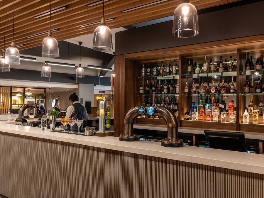 Un espace bar avec un comptoir, plusieurs robinets et une variété de bouteilles d’alcool.