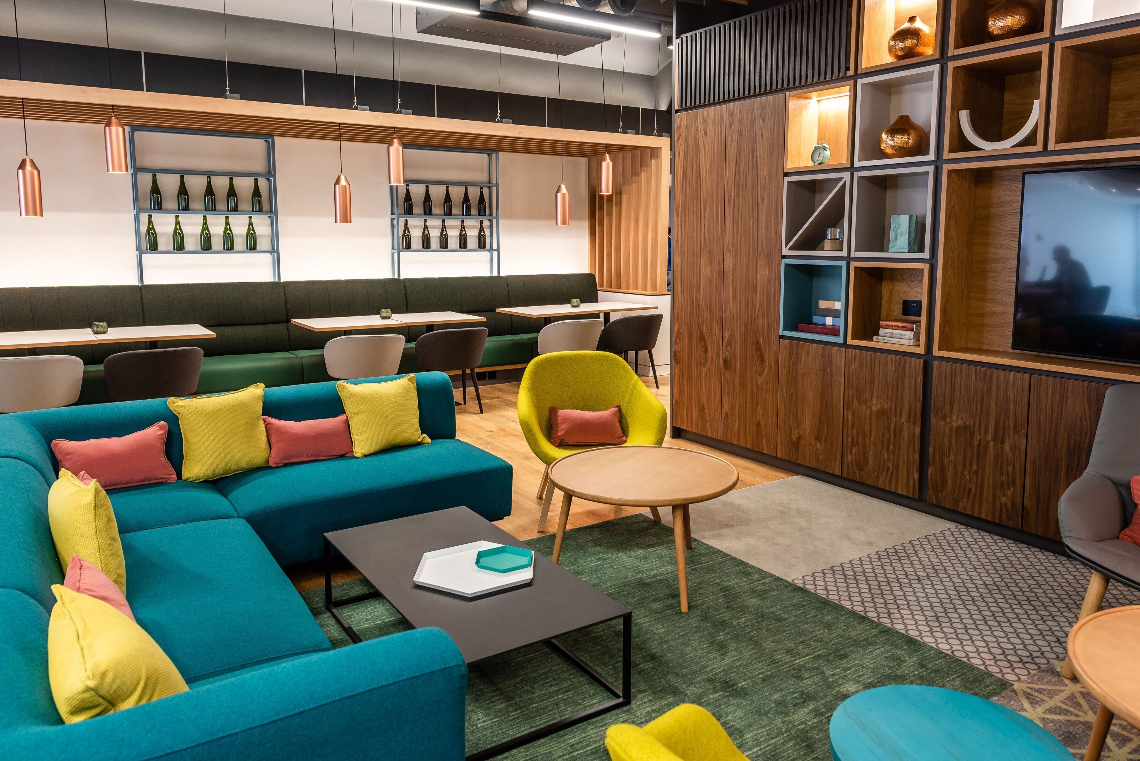 Un espace de détente moderne comprenant un canapé d’angle, des tables rondes et un téléviseur.