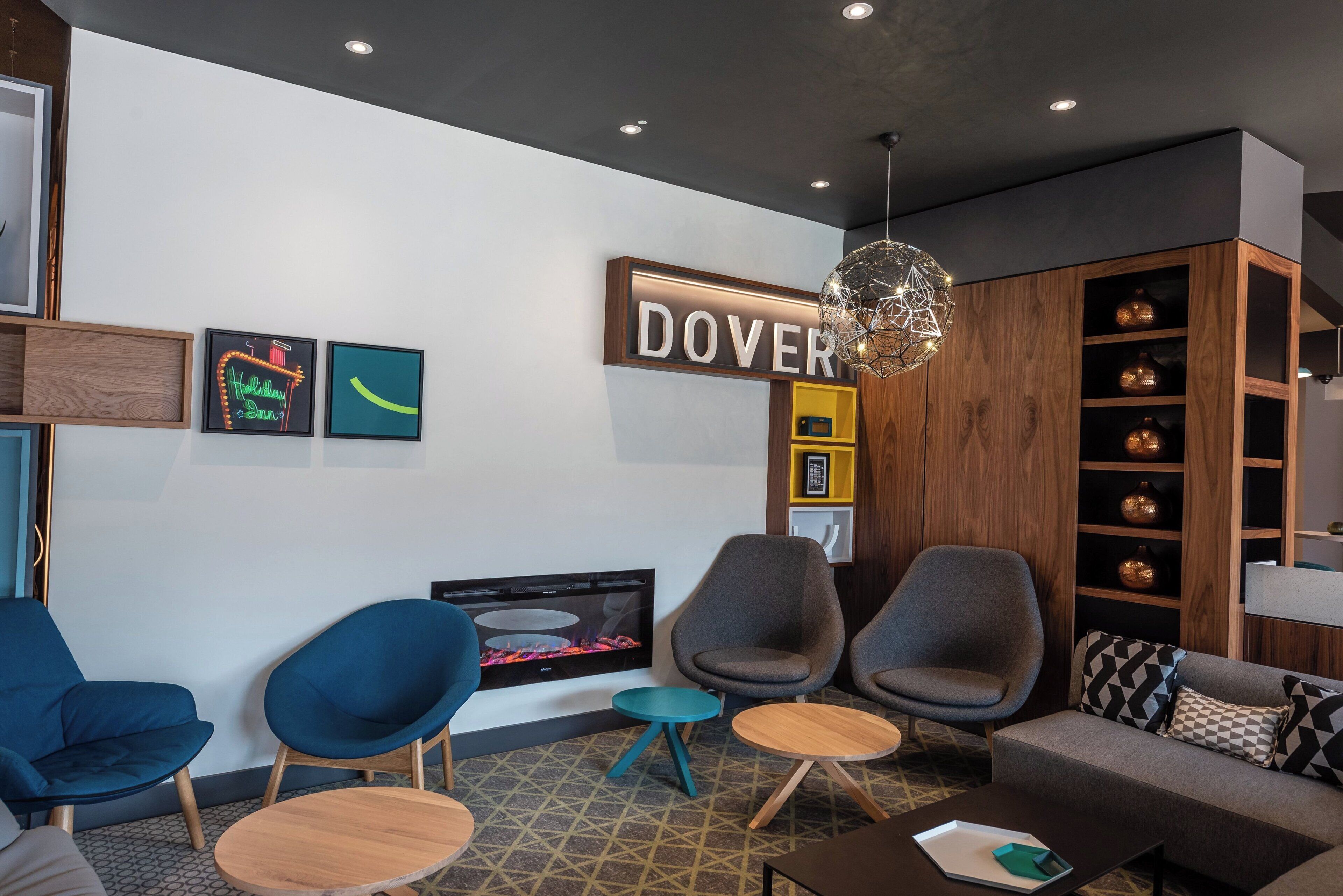 A modern lounge area with seating, a fireplace, and a decorative wall sign.