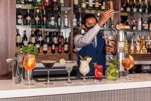 A bar with a variety of cocktails and a bartender preparing drinks.