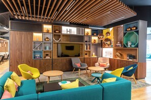 Un espace de détente moderne doté d’un grand téléviseur à écran plat, de lambris en bois et de sièges aux couleurs vives.