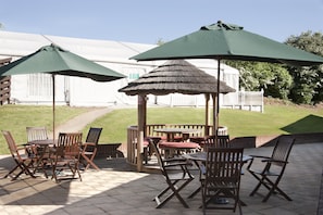 An outdoor patio with wooden furniture and green umbrellas. - Holiday Inn Dover by IHG (Dover)