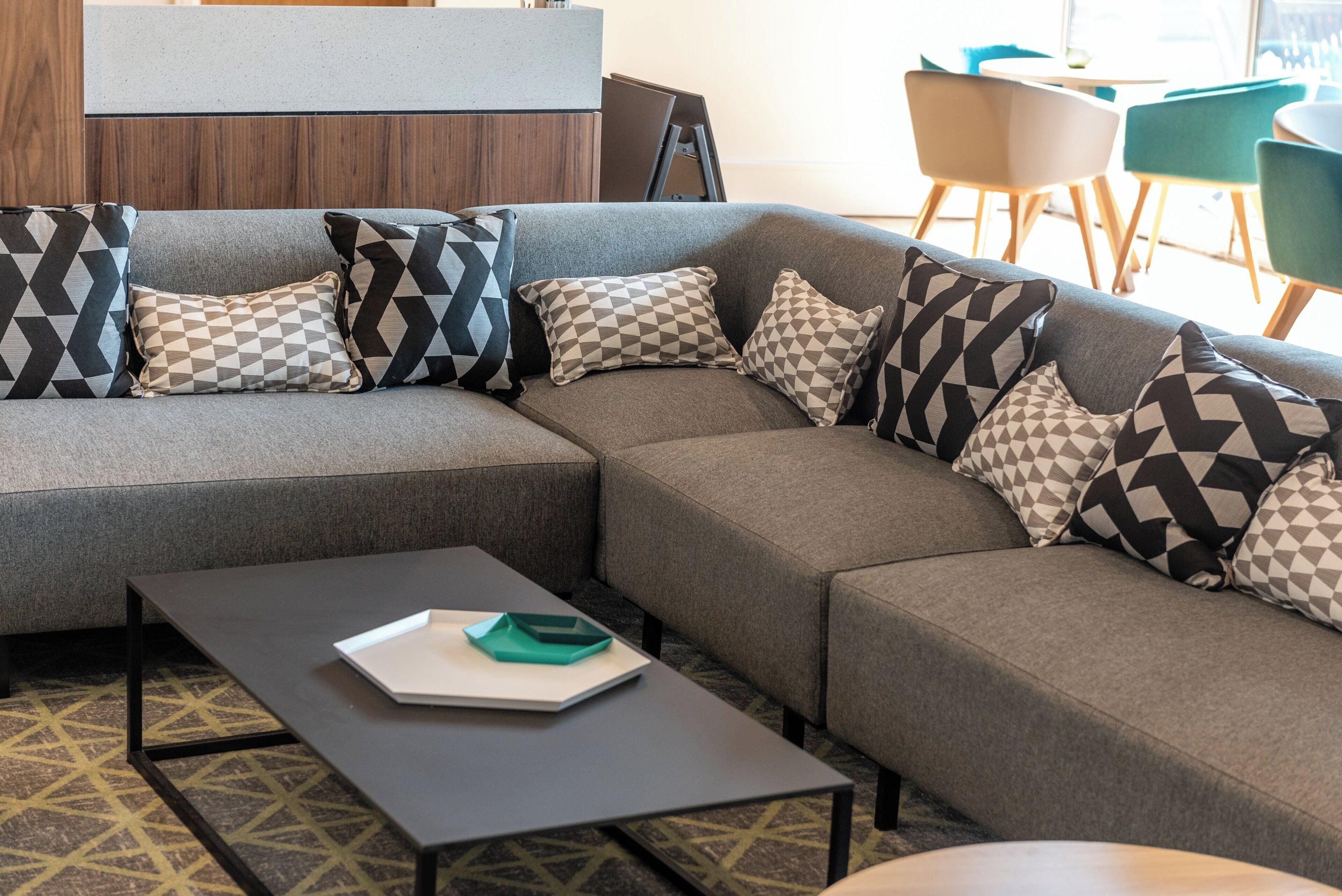 Een moderne zithoek met een modulaire bank, een salontafel en decoratieve kussens met een patroon.