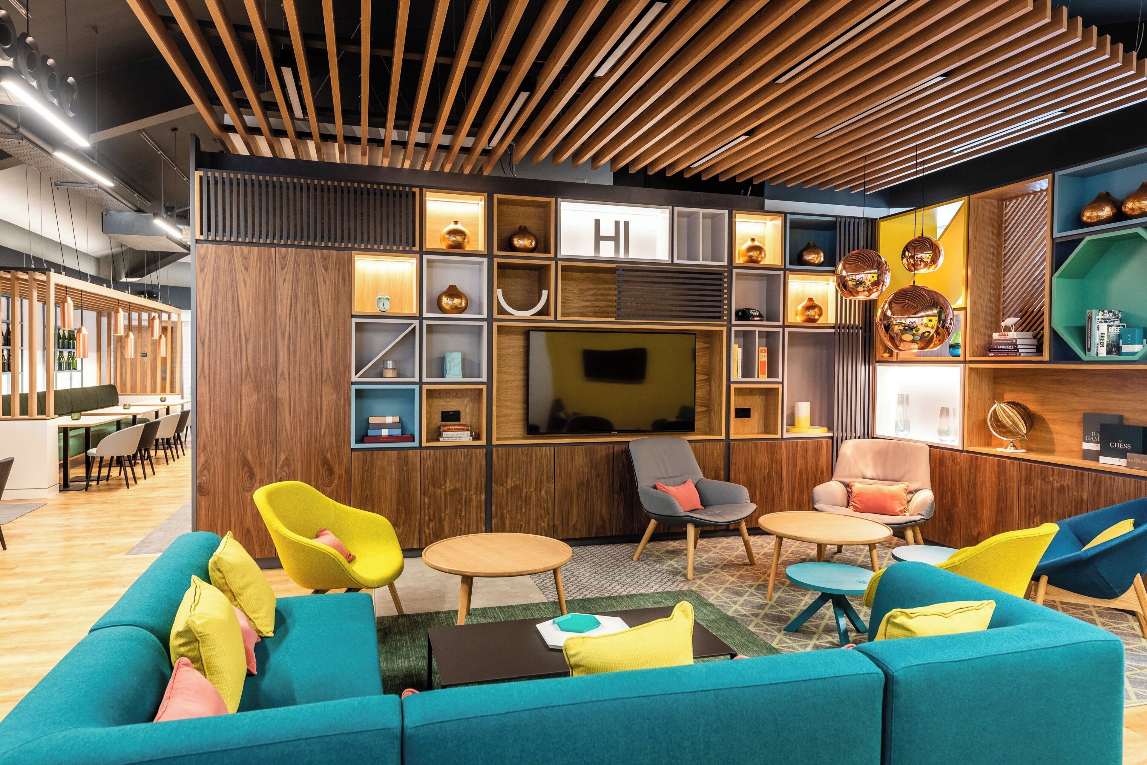 A modern lounge area with a wooden ceiling, comfortable seating, and a television.