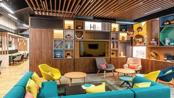 A modern lounge area with a wooden ceiling, comfortable seating, and a television.