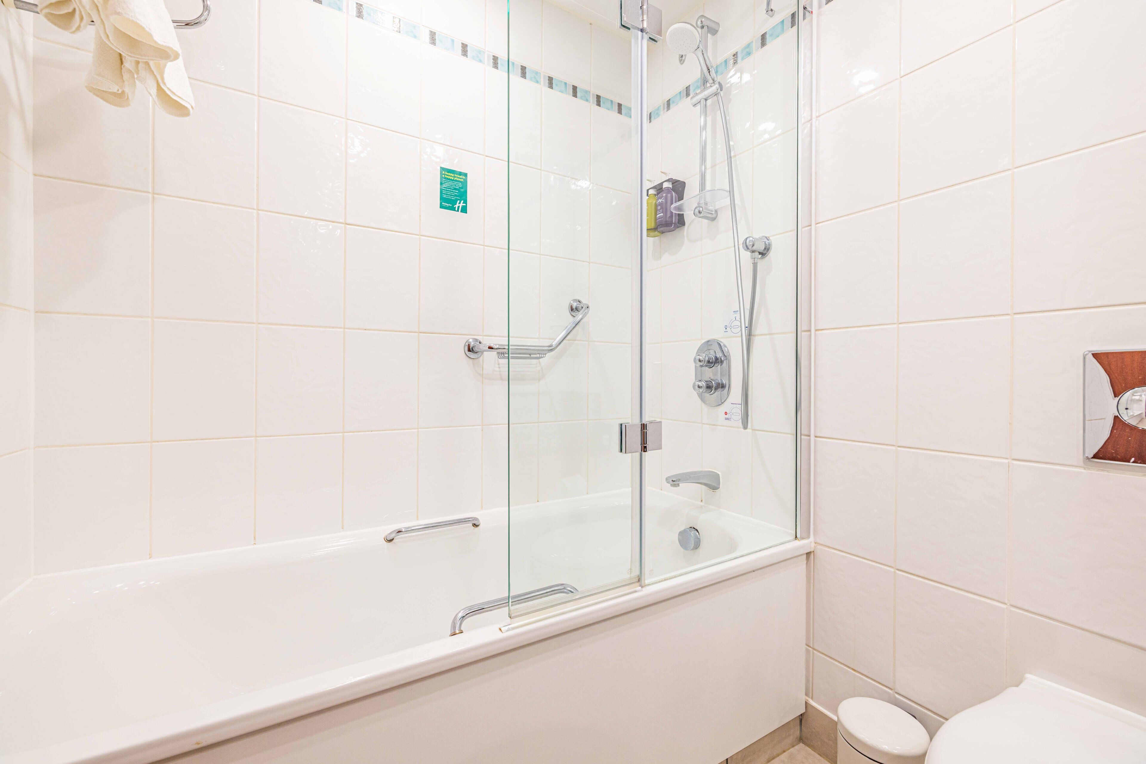 A modern bathroom with a glass-enclosed shower, a white bathtub, and a toilet.