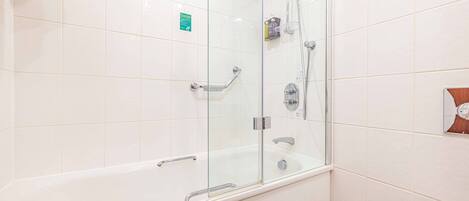 A modern bathroom with a glass-enclosed shower, a white bathtub, and a toilet.