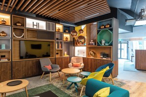 Un interior moderno con techo de madera, estantes empotrados con objetos decorativos, un televisor de pantalla plana y un mobiliario confortable.