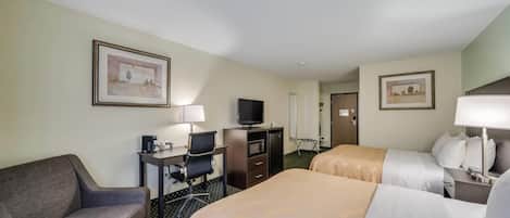 A hotel room with two beds, a desk with a computer, a TV, and a chair.