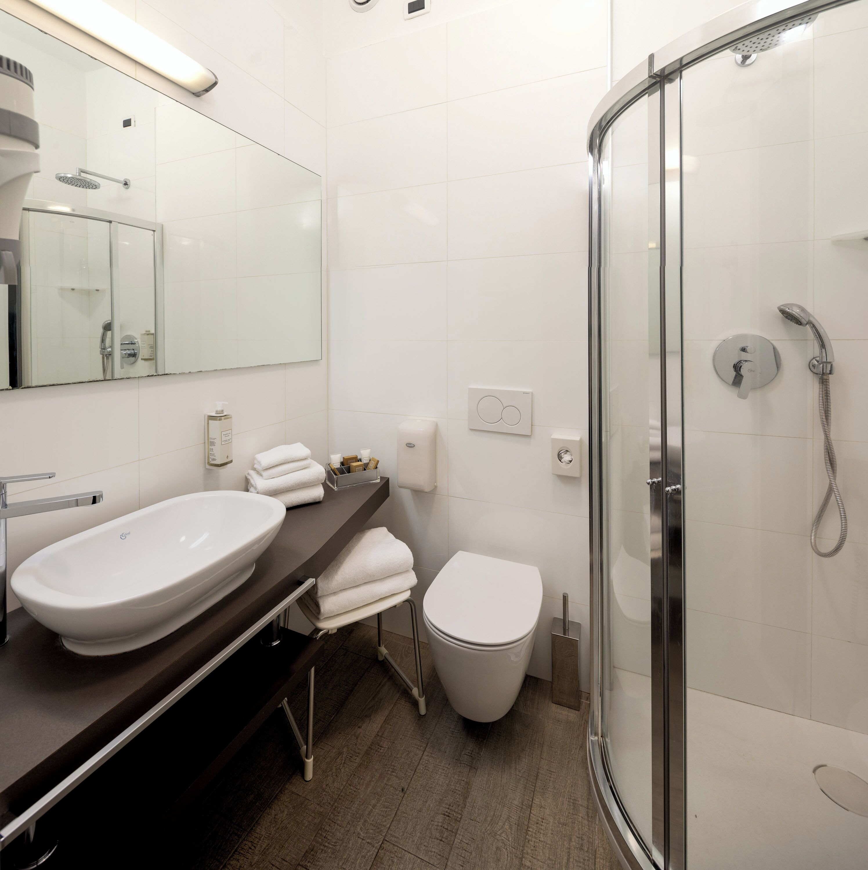 A modern bathroom with a large sink, toilet, and glass-enclosed shower.