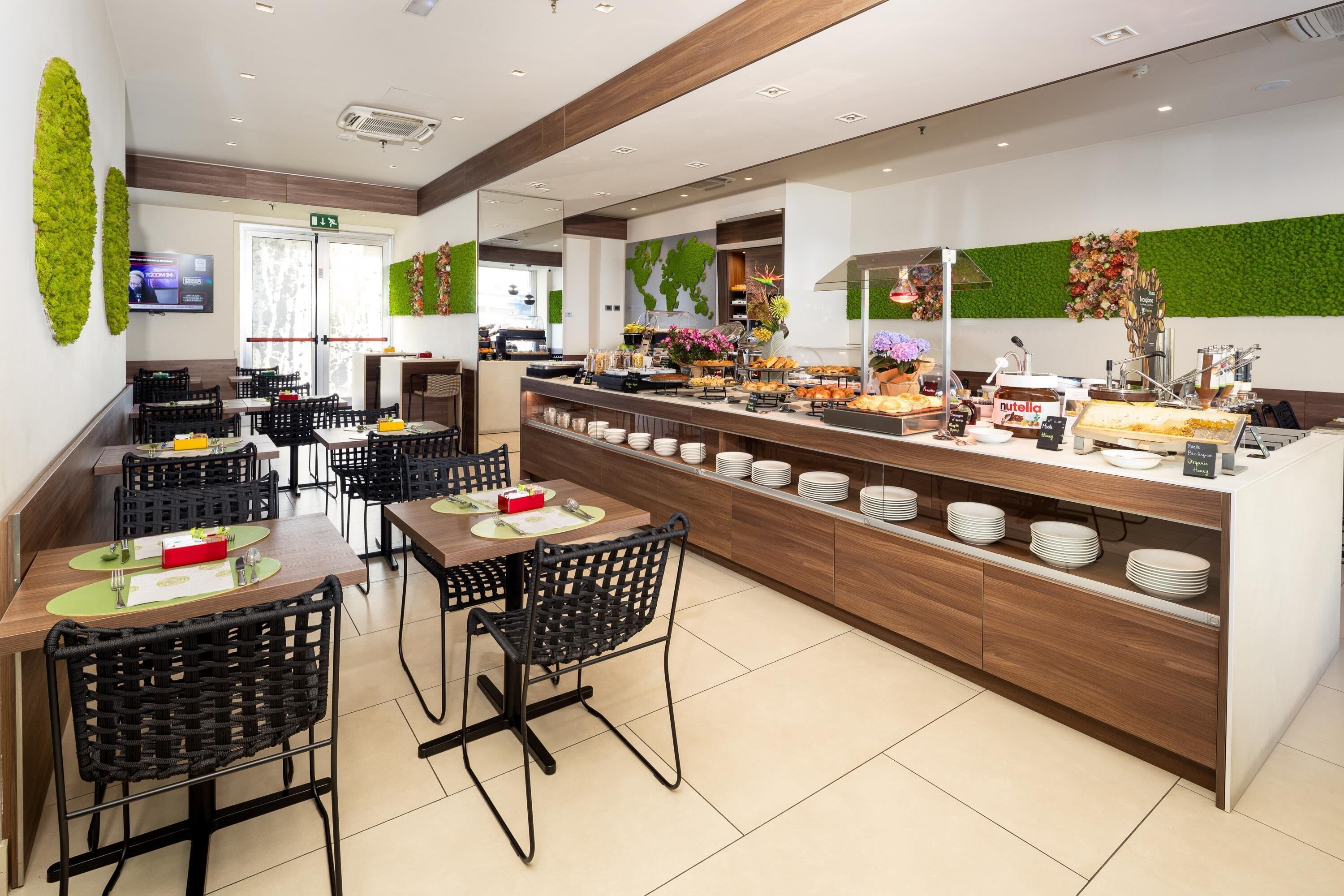 A modern breakfast area with a buffet, black wicker chairs, and a wooden counter with various food items.