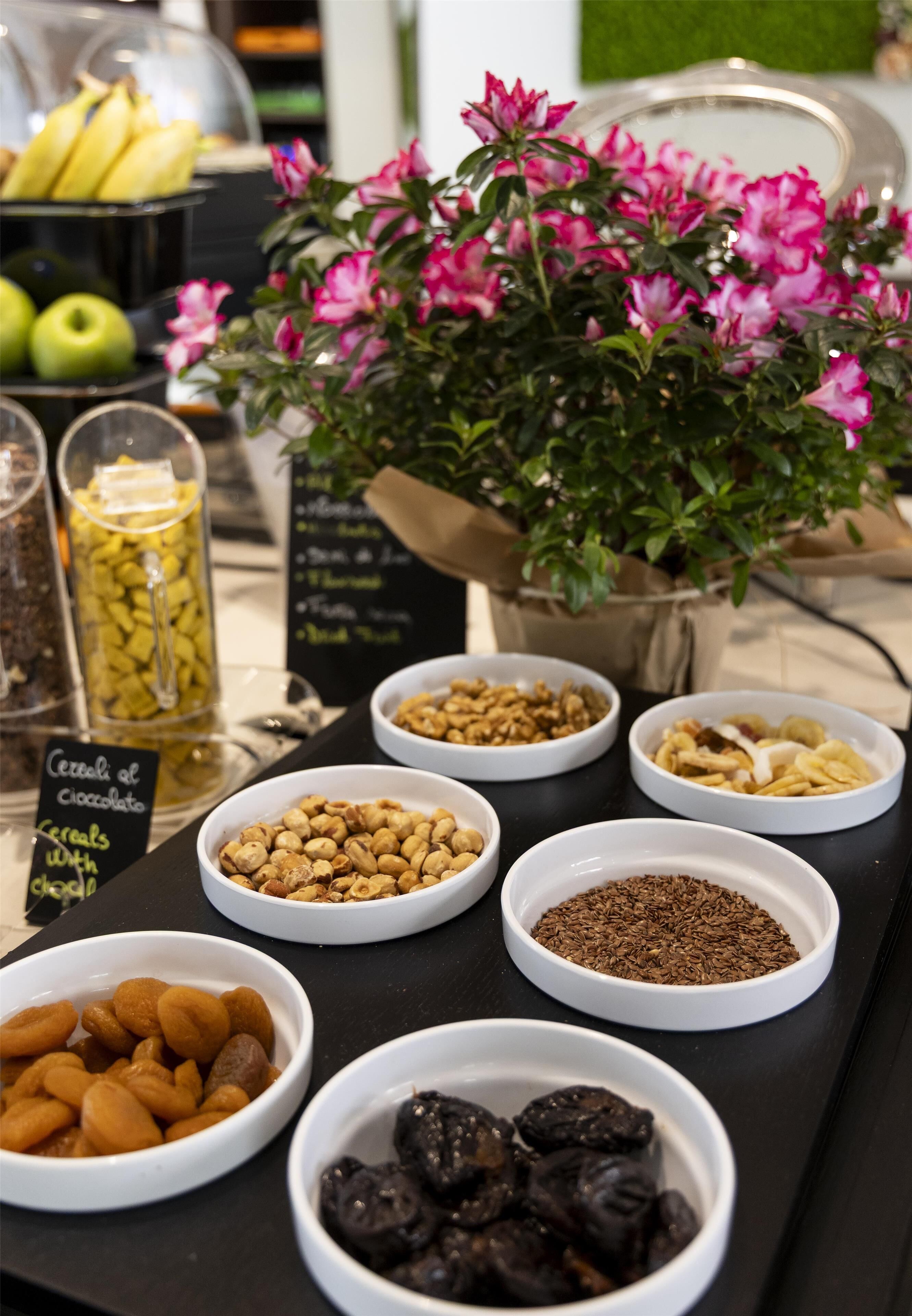 Ein reichhaltiges Buffet mit verschiedenen Speisen und einem Blumentopf mit rosa Blüten.