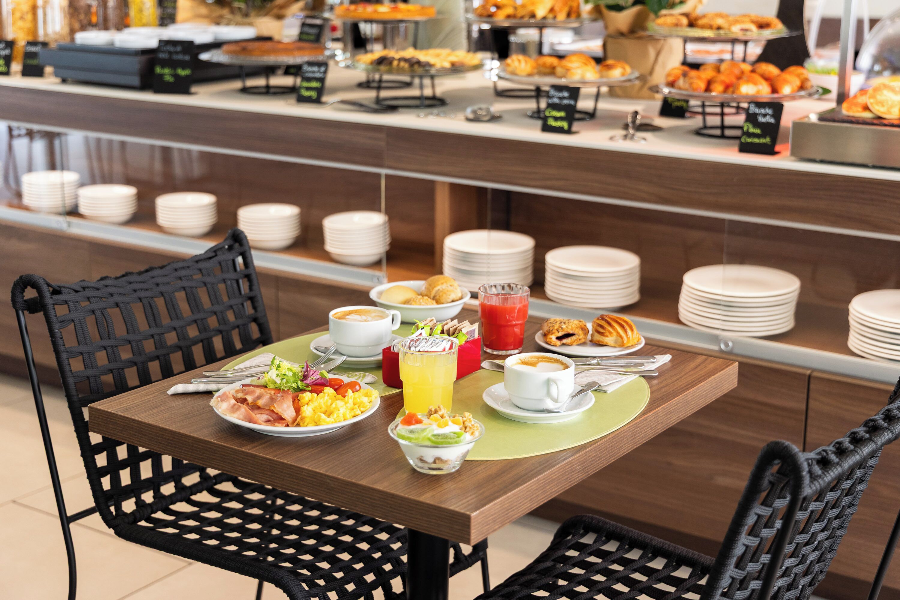 Un buffet della colazione con diversi cibi, piatti e bicchieri su un tavolo.
