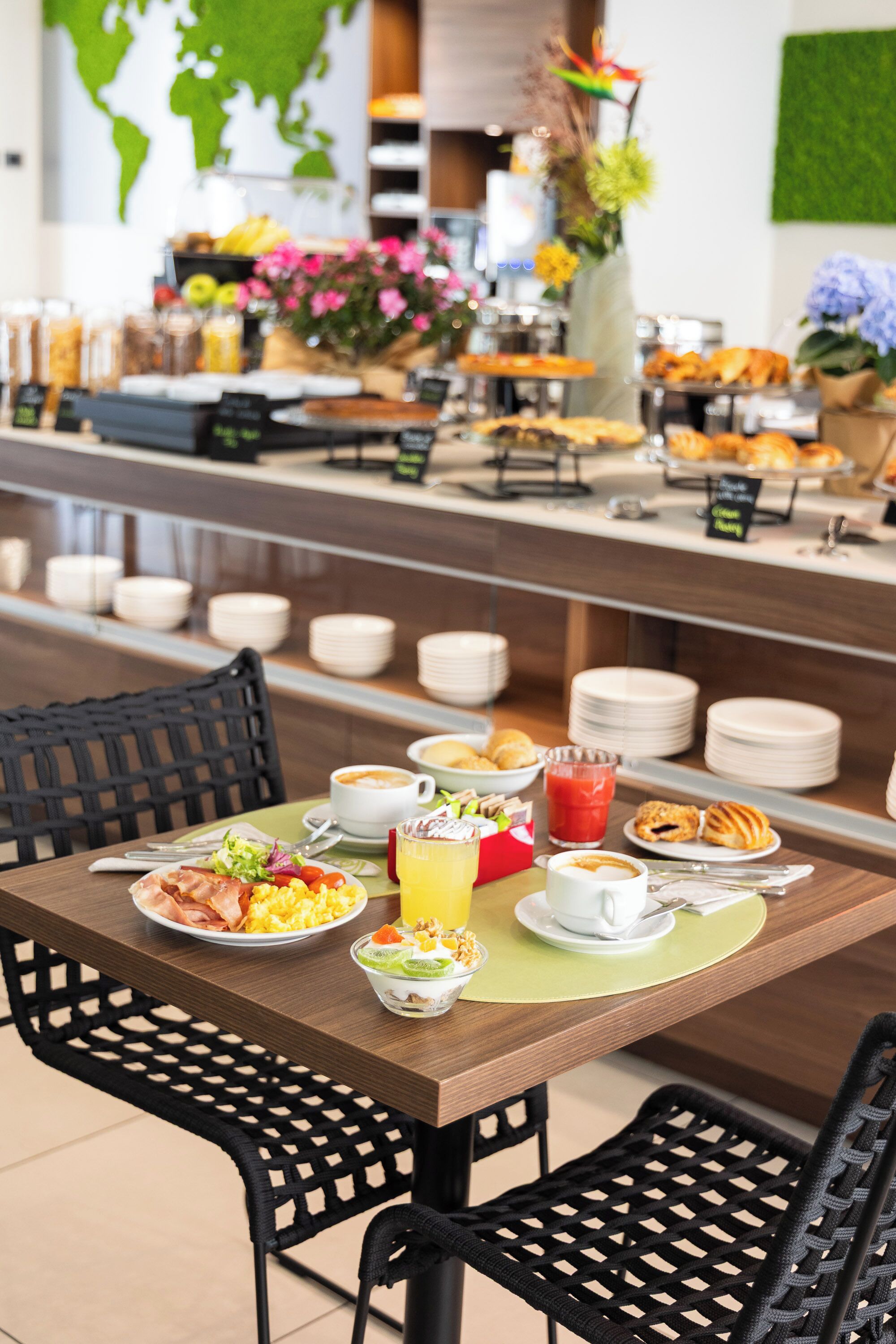 A breakfast buffet with various food items, a coffee station, and a world map on the wall.