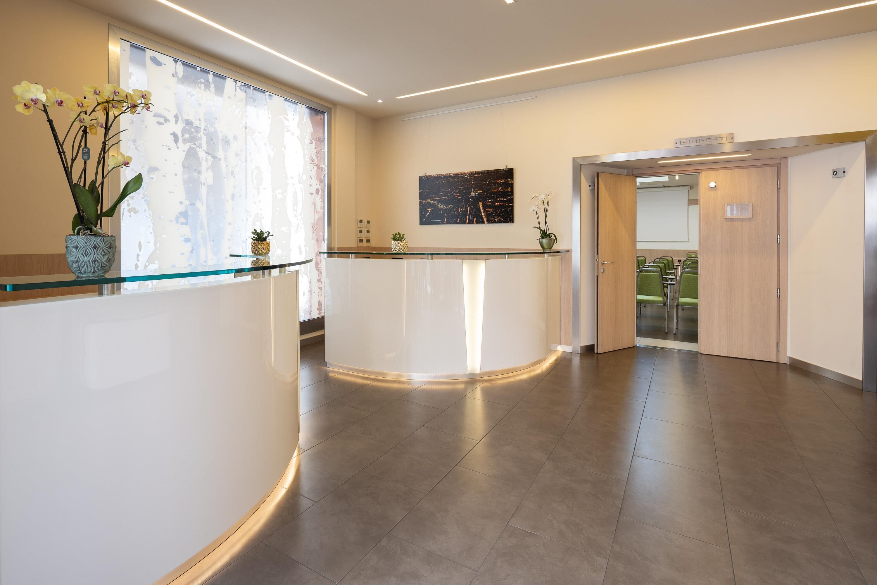 A reception area with a curved reception desk, a large window with curtains, and a framed picture on the wall.