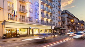A multi-story hotel with balconies, a visible entrance, and a street view with moving traffic. - Best Western Hotel Luxor (Turin)