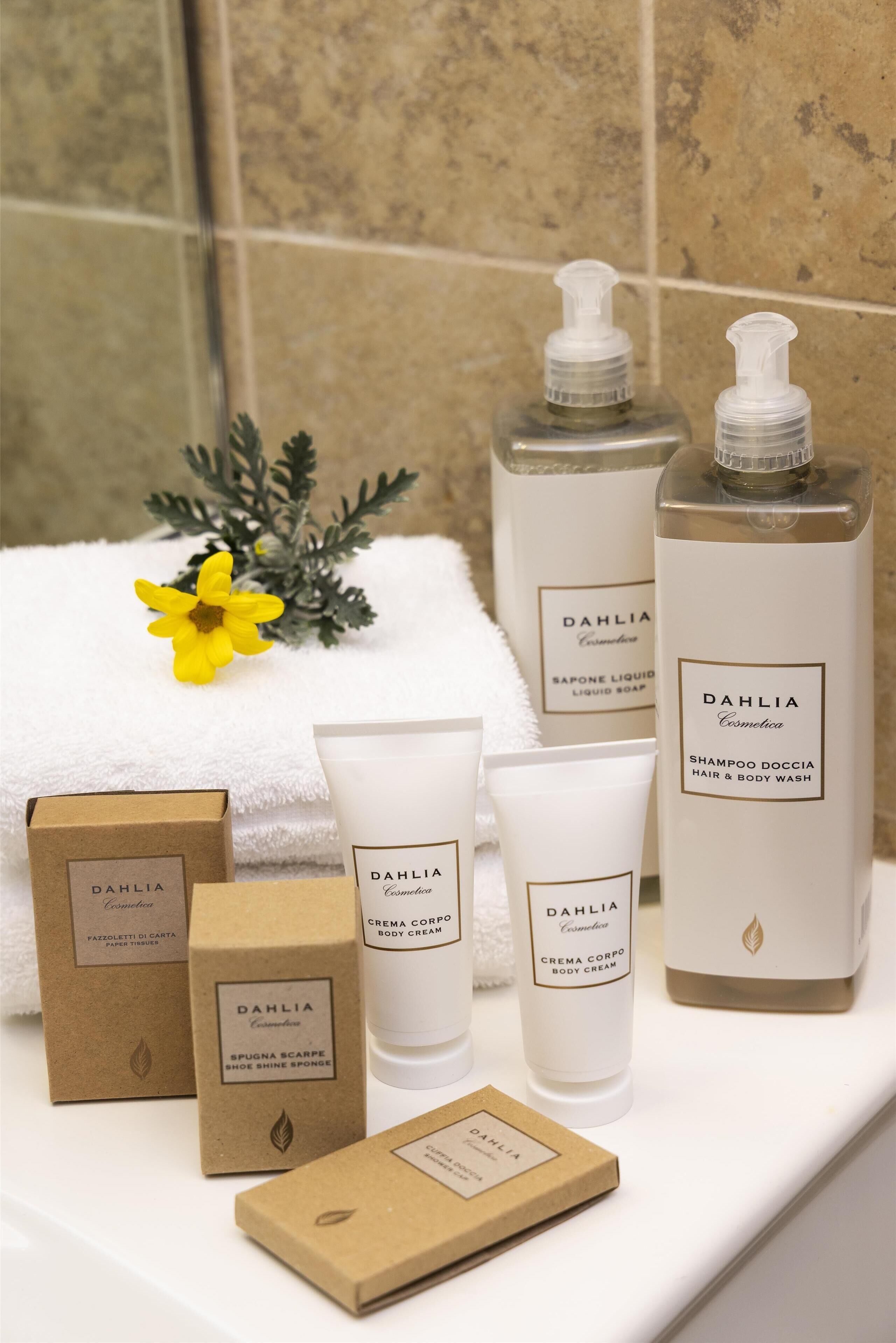A bathroom with toiletries including a shampoo, body wash, and body cream, arranged on a white surface.