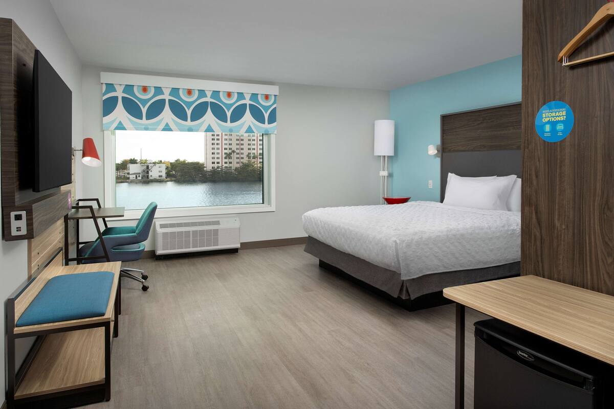 Habitación de hotel con cama, escritorio, silla y vista a un cuerpo de agua.